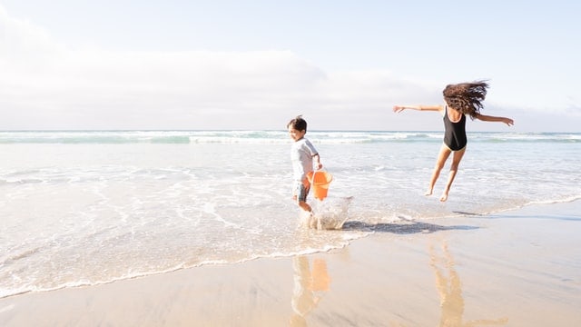 kids playing at beach, wearing sunscreen for protection